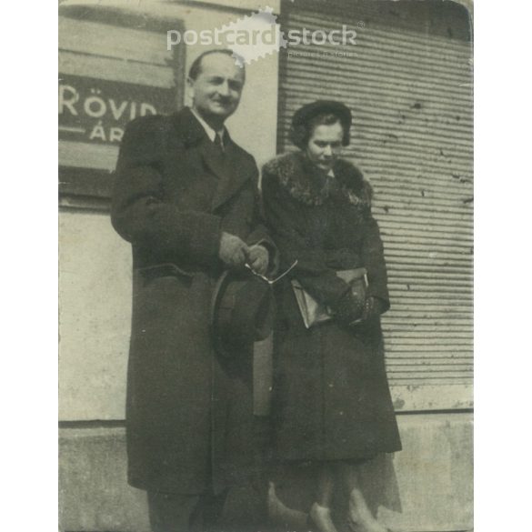 1930s. In the sunshine. Middle-aged couple in front of a haberdashery shop. Original paper image. Its maker is unknown. (2792221)