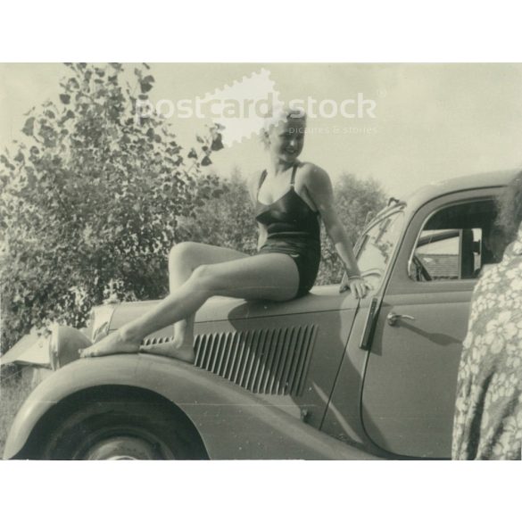 1953 – Germany. Bodensee. Pretty young woman sitting on the car. Its maker is unknown. Black and white original paper image, old photo. (2792425)