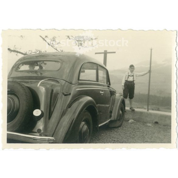 1950s. Germany. A young boy stands in front of a car in the mountains. The creator of the image is unknown. Black and white original paper image, old photo. (2792427)