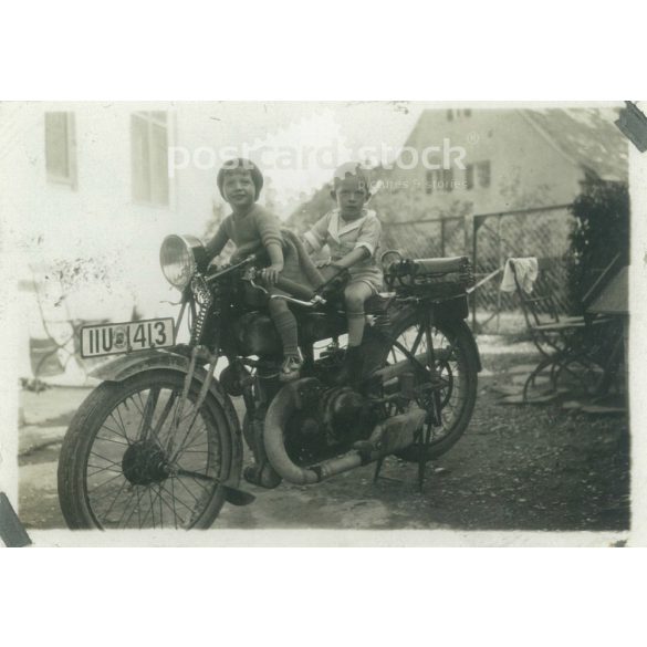 1950s. Germany. Children on a stationary motorcycle in the yard. The creator of the image is unknown. Black and white original paper image, old photo. (2792428)