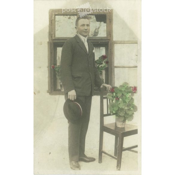 Early 1900s. Young man in front of the house with geraniums. Original paper image. Old photo. Colored, cut photo sheet, old postcard. (2792655)